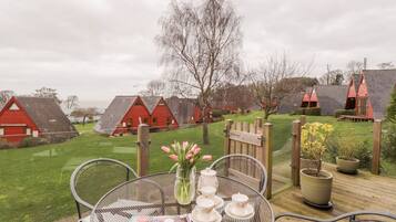 A deck with a table set for tea, surrounded by red-roofed cottages.