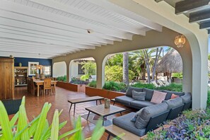 A covered patio area with a dining table, sofa, and chairs.