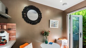 A modern kitchen with a coffee machine, a round mirror, and a small table with a vase of flowers. - Tiny House, Brighton With Parking (Brighton)