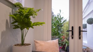 A potted plant on a table near a door, with a view of a garden outside. - Tiny House, Brighton With Parking (Brighton)