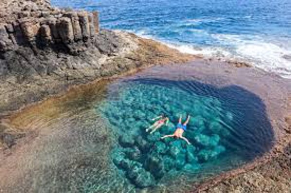 A clear blue pool surrounded by rocky terrain.