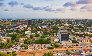 A cityscape with a mix of residential and commercial buildings, a prominent modern glass building, and a railway track running through the center. - Lovely Apartment Bargain Rate, Accra, Ghana (Kwabenya)