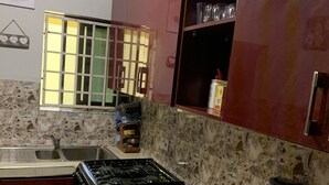 A kitchen with a gas stove, a sink, a refrigerator, and a blender on the counter. - Lovely Apartment Bargain Rate, Accra, Ghana (Kwabenya)