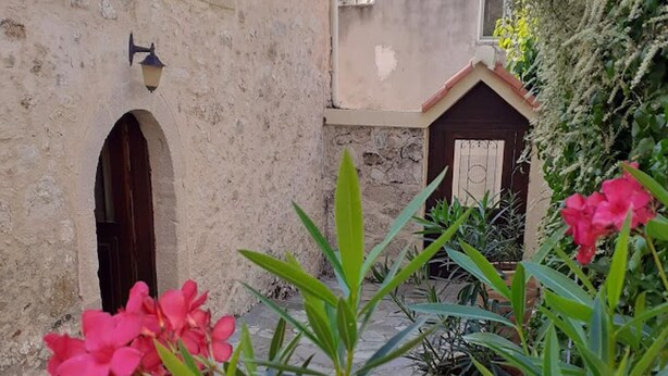 Un patio con suelo de piedra, plantas en macetas y un edificio de aspecto rústico.