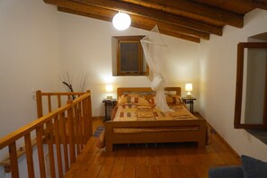 Une chambre à coucher avec un lit en bois, deux lampes de chevet, une rambarde en bois et une petite fenêtre avec un rideau.