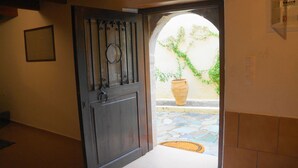 Una entrada con puerta de madera oscura, suelo de baldosas y planta en maceta.