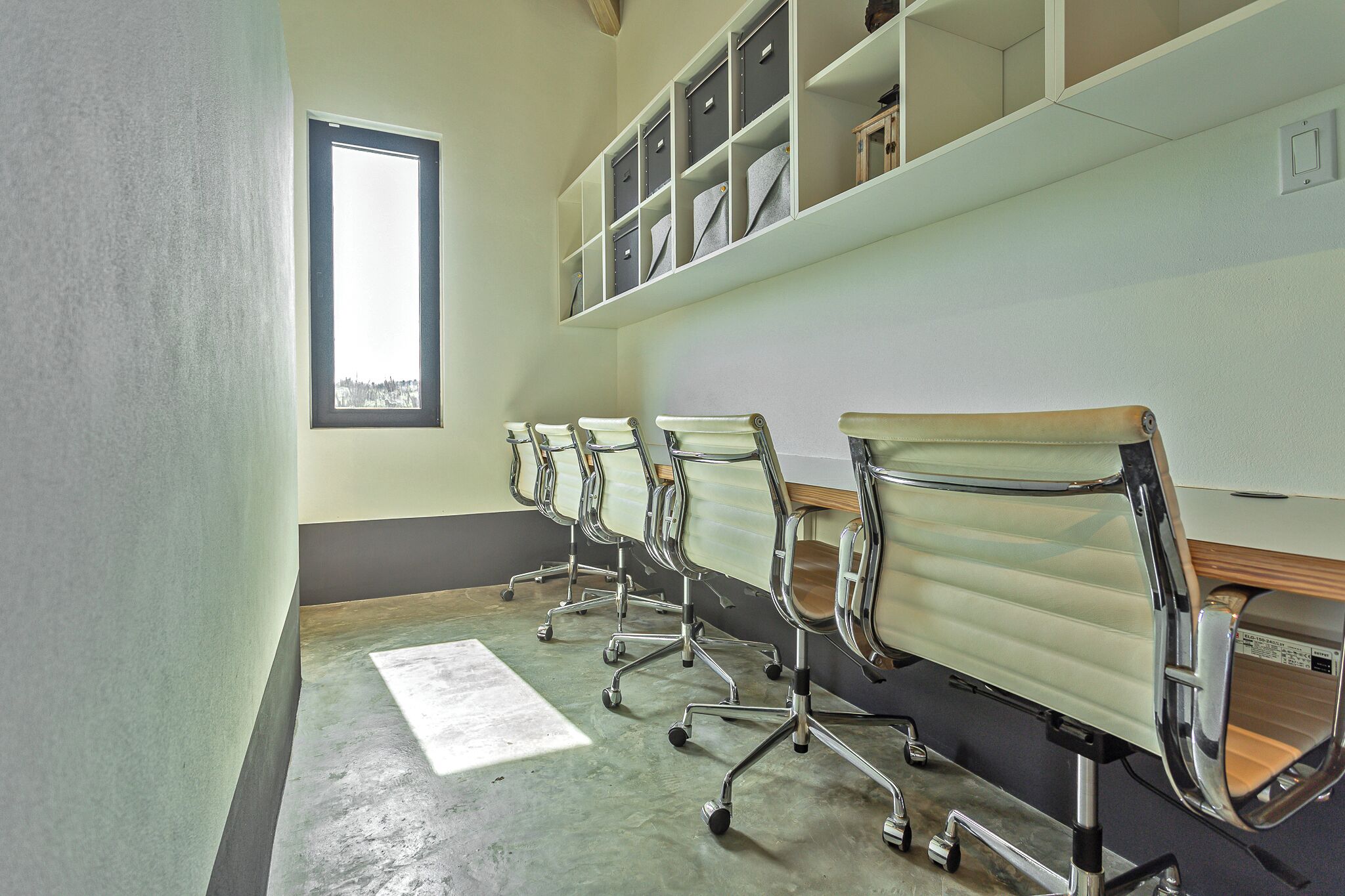 Une salle de conférence avec une rangée de chaises de bureau, une grande fenêtre et des étagères.