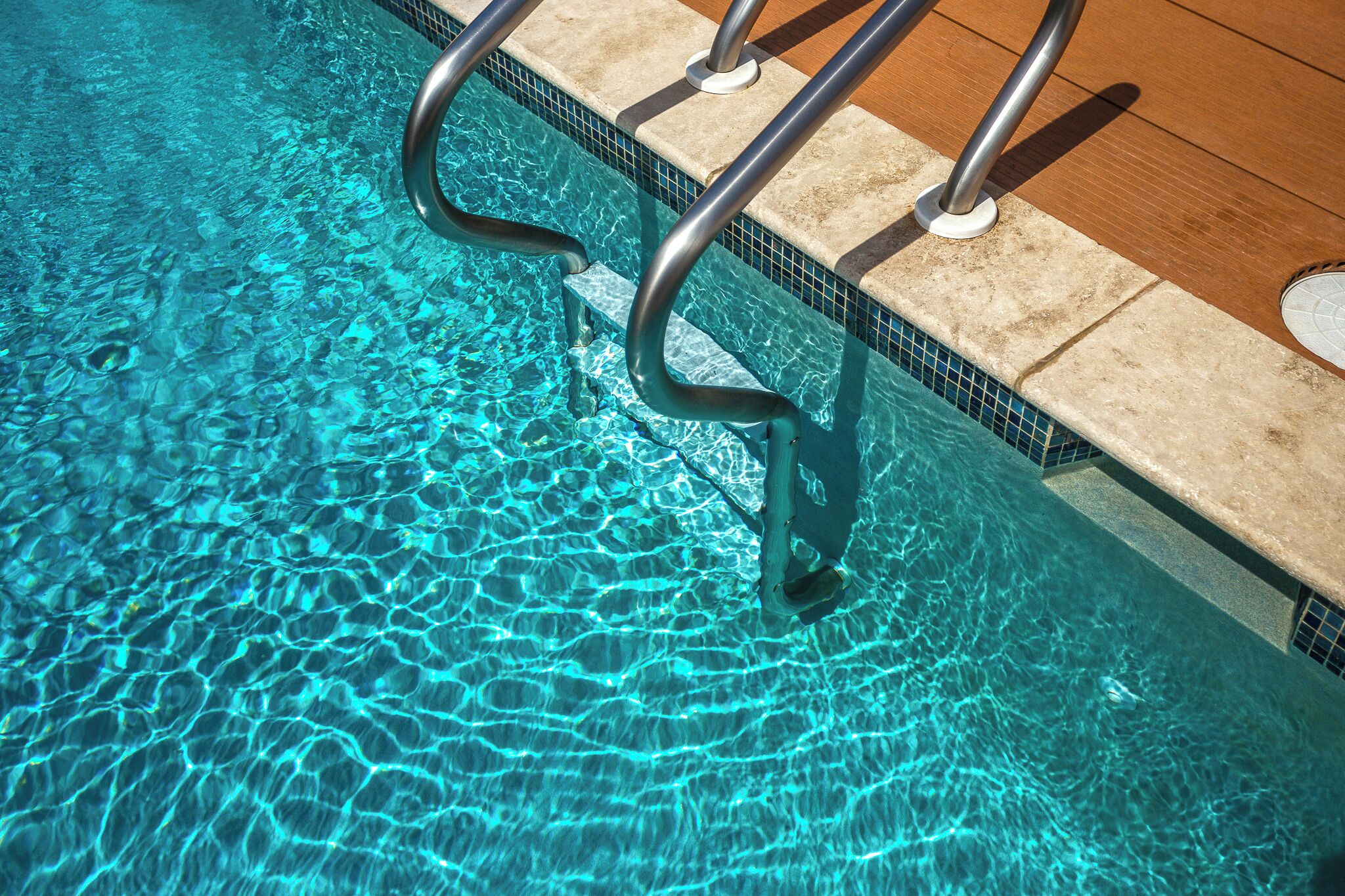 A clear blue pool with a metal ladder leading into it.