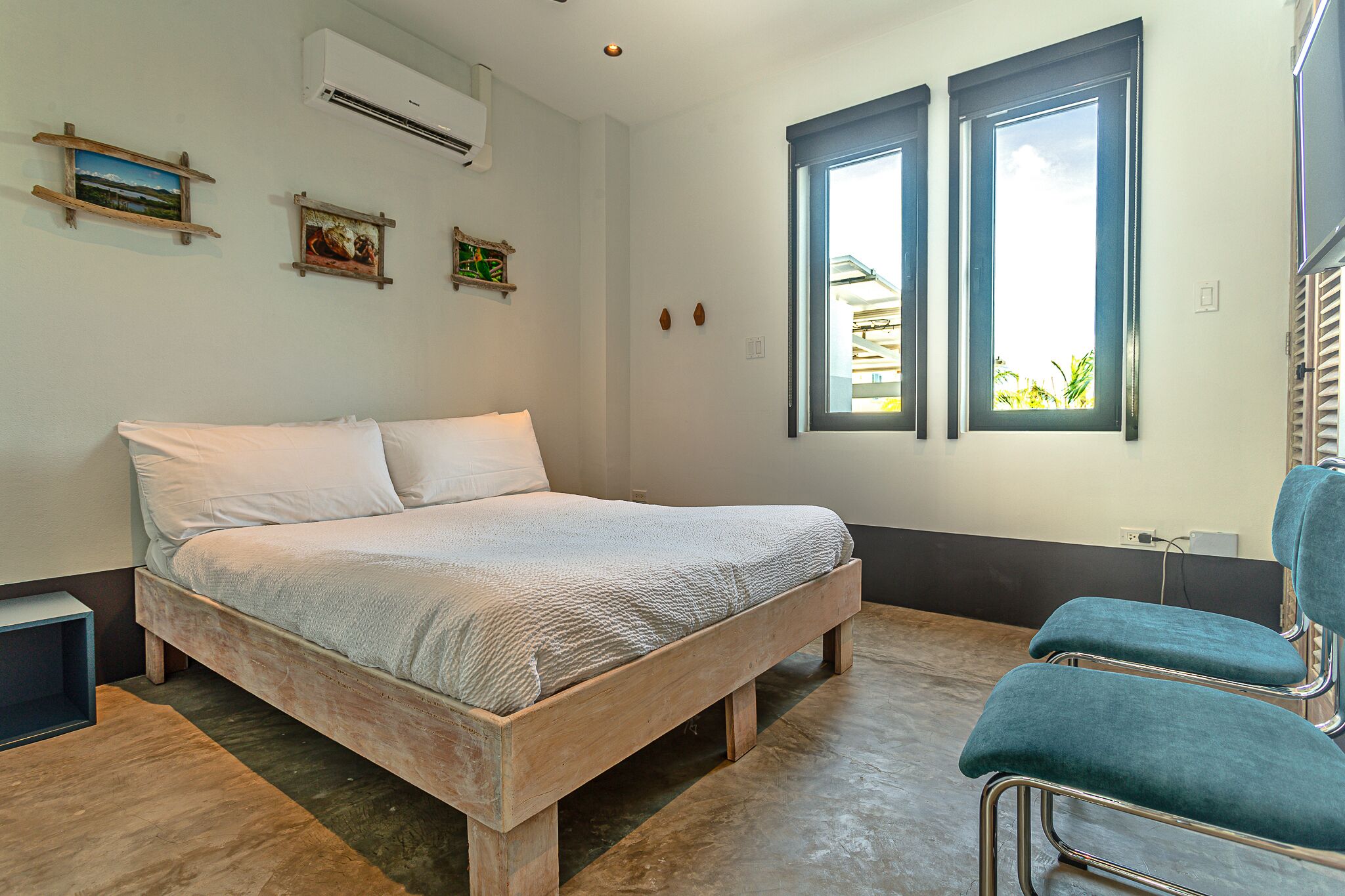 A bedroom with a wooden bed, two windows, and a chair.