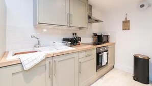 A modern kitchen with light-colored cabinets, a stainless steel sink, a toaster, a microwave, and a trash bin. - Hidden Hot Tub Retreat Apartment in Nottingham (Nottingham)