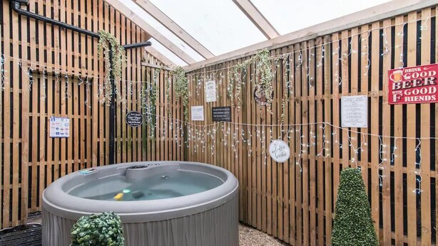 A hot tub area with wooden walls, string lights, and small potted plants. - Hidden Hot Tub Retreat Apartment in Nottingham (Nottingham)