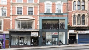 A street view of a row of buildings with various storefronts, including a shop with a 'Page 45' sign and another with a 'News' sign. - Hidden Hot Tub Retreat Apartment in Nottingham (Nottingham)