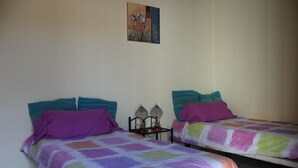 A room with two beds, each with colorful bedding and pillows. There is a wall-mounted artwork above the beds. - Rustic 1-bed Bungalow in Parque Holandés (La Oliva)