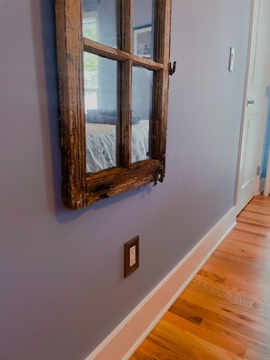 Una habitación con ventana de madera, pared azul claro y suelo de madera.