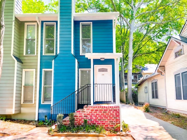 Une maison à deux étages, avec une façade bleue et un porche avant en briques rouges.