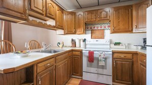 A kitchen with wooden cabinets, a white countertop, a sink, a stove, and a red towel hanging on the oven. - 16 Apartment near Acadia Open Hearth Inn (Trenton)