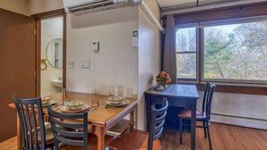 A dining area with a wooden table, chairs, and a window with a view of trees. - 16 Apartment near Acadia Open Hearth Inn (Trenton)