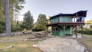 Un rustico chalet con patio in pietra, terrazza in legno e tavolo da picnic.