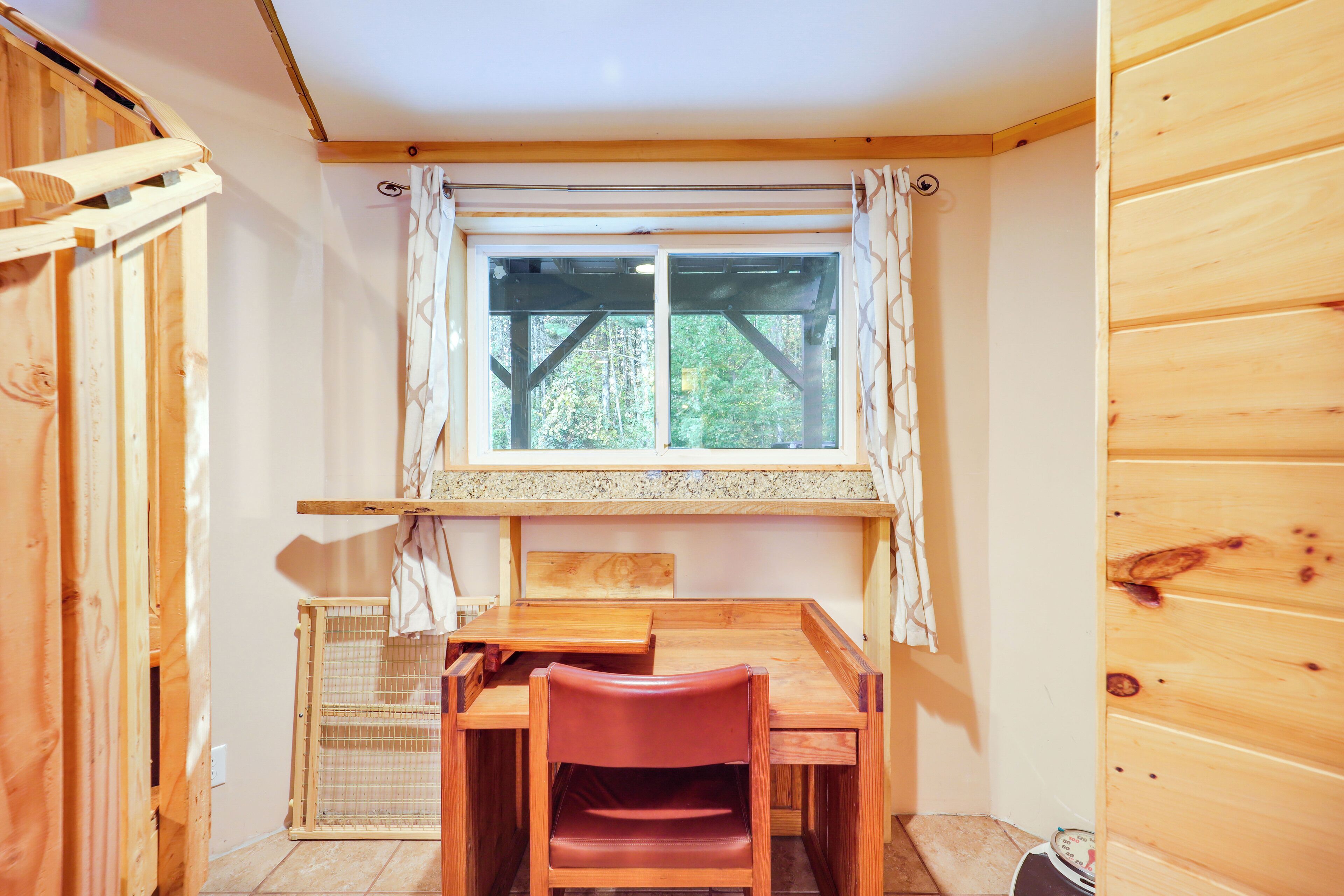 A wooden room with a window, a table, and a chair.