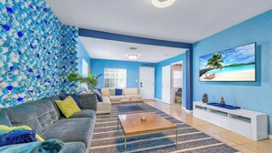 Ein Wohnzimmer mit Sofa, Couchtisch und Fernseher an der Wand.