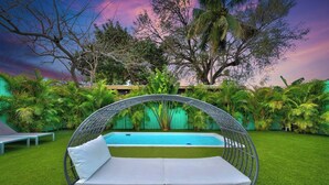 Ein Garten mit Pool, einer Hängematte und einer Bank.