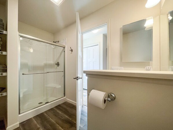 A bathroom with a glass shower enclosure, a toilet paper holder, and a mirror. - Newly Built Lake Front Home (Lake Pleasant)