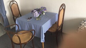 A dining table with a checkered tablecloth, surrounded by wicker chairs. A vase with purple flowers is on the table. - Helene - Sylt - Relaxed island life: Cozy vacation apartment in Westerland (Sylt)
