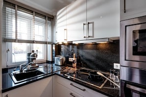 Eine moderne Küche mit schwarzem Arbeitsplatz, Edelstahlgeräten und einem Fenster mit Jalousien.