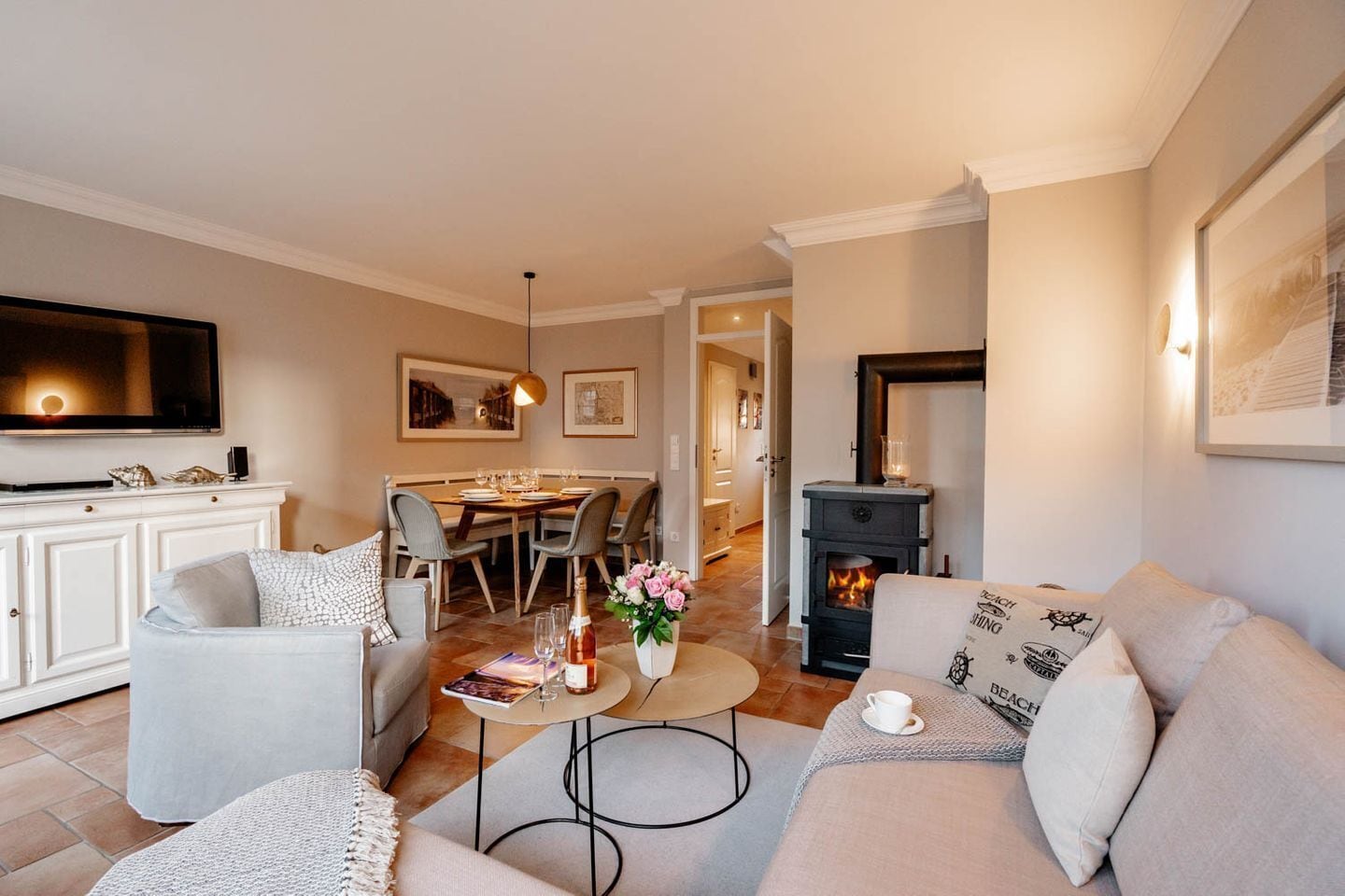 A living room with a sofa, a coffee table, and a fireplace. There is a dining area with a table and chairs in the background.