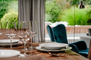 A dining table set with plates, glasses, and cutlery, with a view of greenery and a chair in the background. - Oene - Welcome to the vacation home "Oene" in Tinnum! (Sylt-Ost)