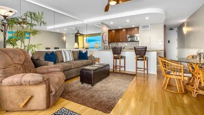 A modern living room with a sofa, ottoman, and dining area with chairs and a table.