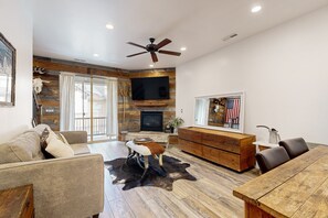 Relax in this cozy living space with a large flat-screen TV, leather sofa, and dining table.