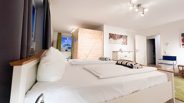 A modern hotel room with a large bed, a wooden wardrobe, a desk, and a chair. - Blaue Huis ground floor with sauna - Welcome to the "Blaue Huis" (Sylt)