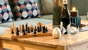 A wooden coffee table with a chessboard, a vase with dried flowers, a candle, and a glass. - Blaue Huis ground floor with sauna - Welcome to the "Blaue Huis" (Sylt)