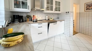 A modern kitchen with white cabinets, a wooden countertop, and a tiled backsplash. - Blaue Huis ground floor with sauna - Welcome to the "Blaue Huis" (Sylt)