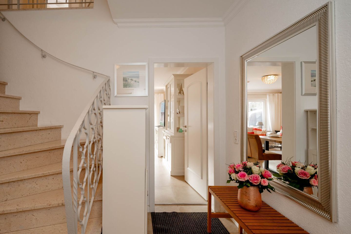 A staircase leading to a hallway with a wooden table and a vase of flowers.