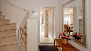 A staircase leading to a hallway with a wooden table and a vase of flowers. - Haus Sprotte - Welcome to the "Sprotte" house (Sylt-Ost)