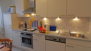 Una cocina moderna con armarios blancos, un lavamanos de acero inoxidable y un horno empotrado.
