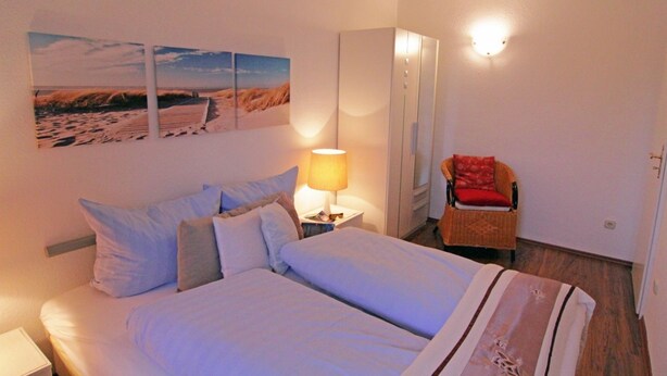 Una habitación de hotel con una cama, una mesita de noche con lámpara, una silla y un armario.