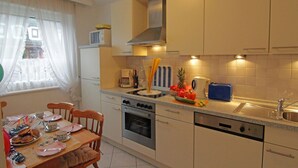 Una cocina compacta con comedor, que incluye estufa, horno, pileta y un refrigerador pequeño.