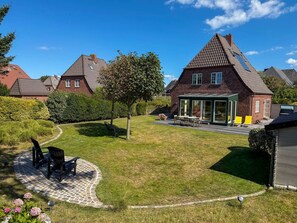 A residential property with a well-maintained lawn, a patio area with outdoor furniture, and a conservatory.