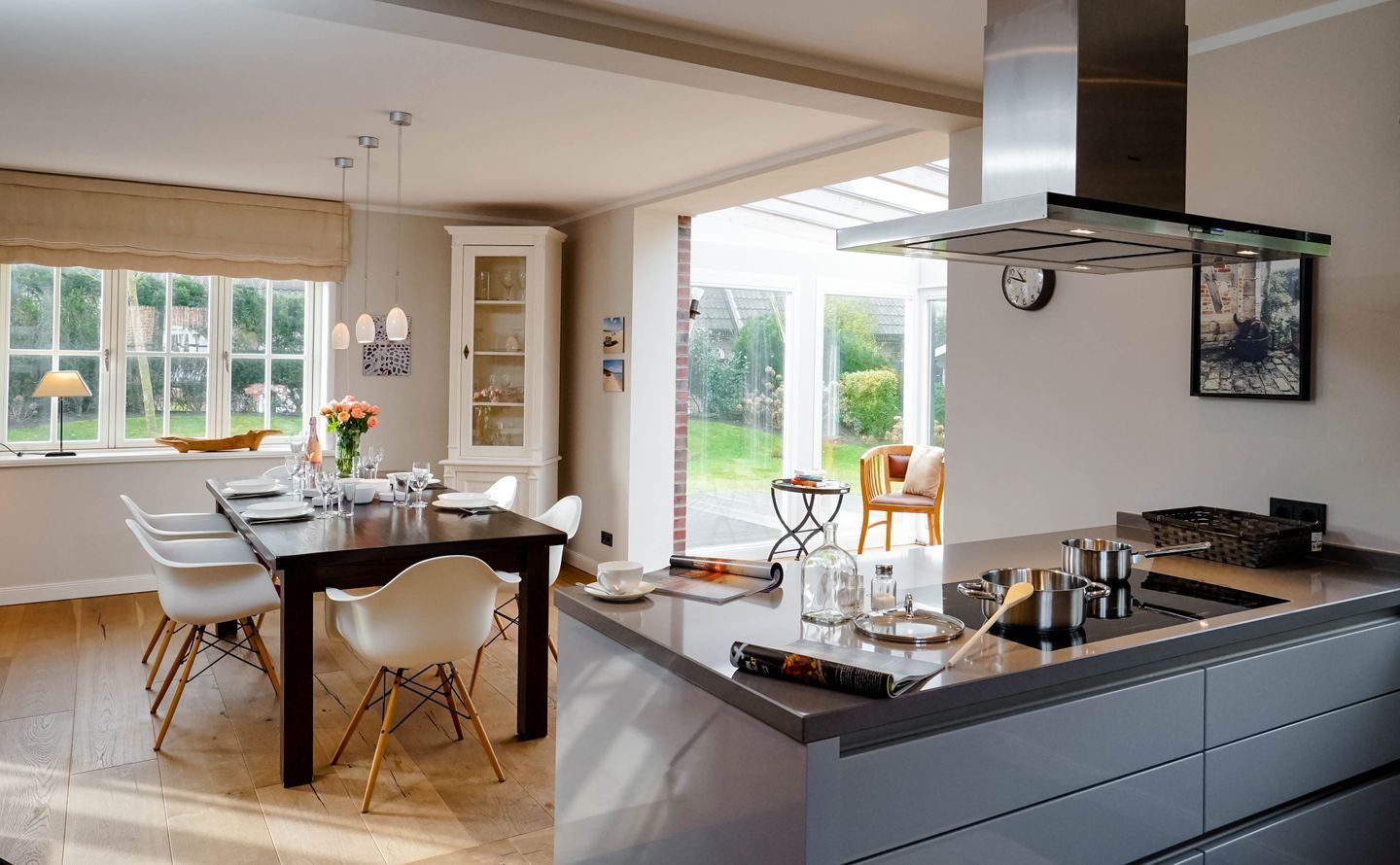 Una cocina moderna con una isla central, comedor con sillas blancas y vistas al exterior.