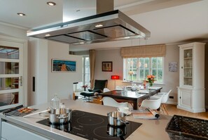 A modern kitchen with a central island, built-in oven, and a dining area with a table and chairs.