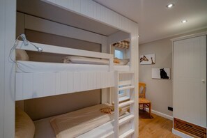 A bunk bed room with a wooden chair and a door. - Beachfront Lodge on Sylt with Sauna - Welcome to the Luxury Vacation Home (Sylt)