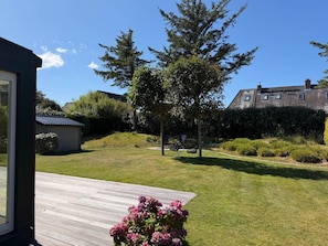 A residential property with a wooden deck, a lawn, and a garden with pink flowers. - Seaside Lodge Sylt with sauna - Welcome to the luxury vacation home (Sylt)