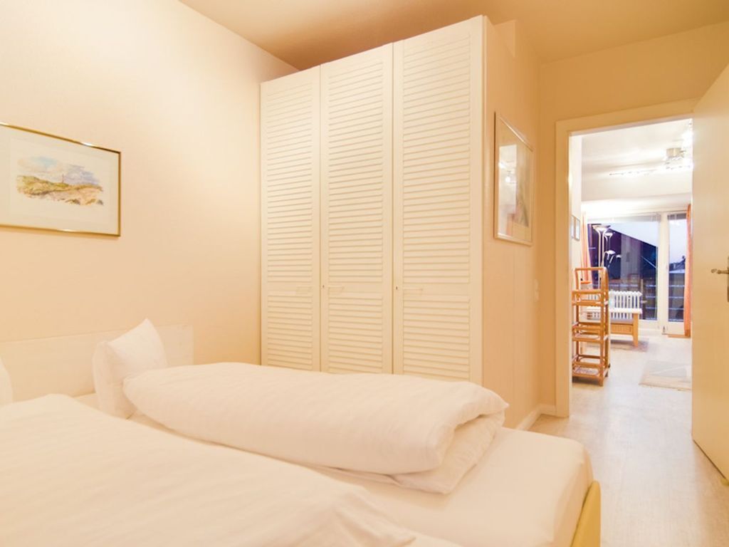 Ein Schlafzimmer mit zwei Betten, einem großen Kleiderschrank und einem Flur, der zu einer Treppe führt.