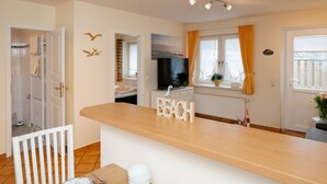 A modern kitchen with a wooden countertop, a television, and a window with curtains. - Godewind ground floor - Moin Moin and welcome to the ground floor 3-room (Sylt-Ost)