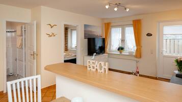 A modern kitchen with a wooden countertop, a television, and a window with curtains.
