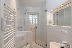 Ein modernes Badezimmer mit Duschkabine aus Glas, einer Badewanne, einer Toilette und einem Waschtisch mit Spiegel.