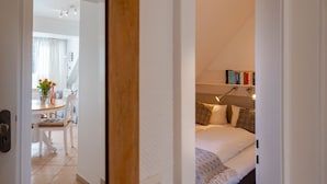 Un dormitorio con cama, mesita de noche, lámpara y estanterías.